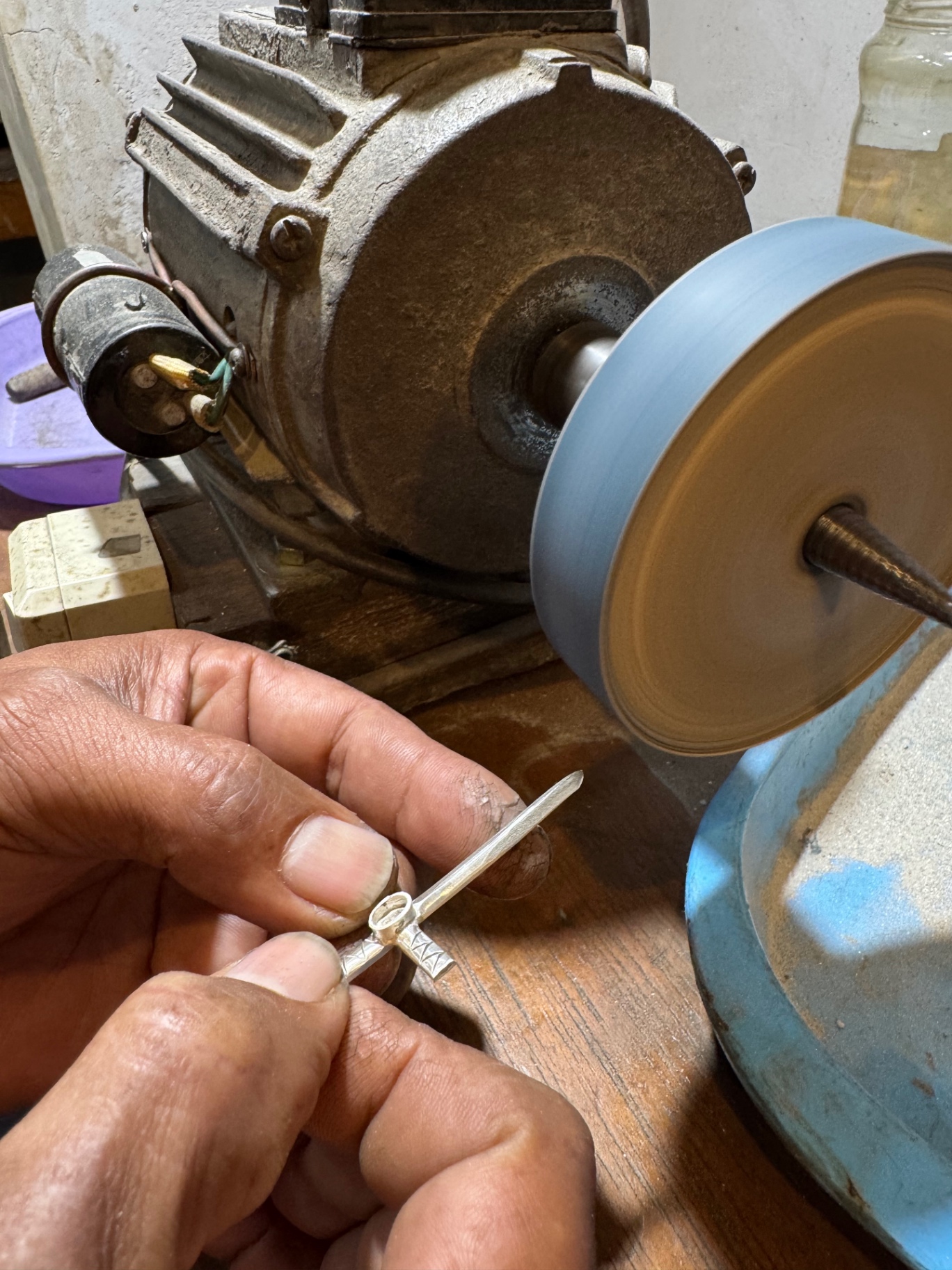 The silver cross being polished on a rotating wheel