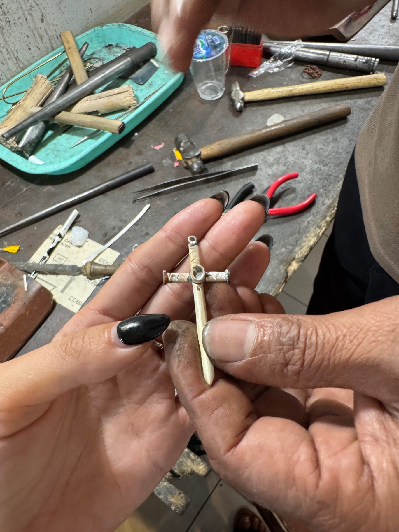 The natural sapphire being fitted into the centre of the silver cross